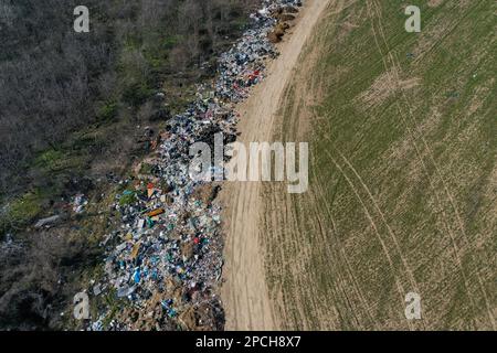 Erstaunliche Umweltverschmutzung in Ungarn. In der Nähe einer Stadt liegt eine Menge Müll neben einer unbefestigten Straße an der Grenze. Umweltverschmutzung. Illegales Dumping. Stockfoto