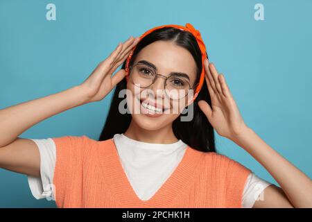 Junge Frau mit stilvollem Bandana auf hellblauem Hintergrund Stockfoto