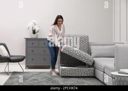 Frau schließt modularen Sofabereich mit Stauraum im Wohnzimmer Stockfoto