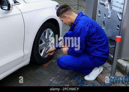 Professioneller Mechaniker, der Reifen beim Autoservice aufpumpt Stockfoto