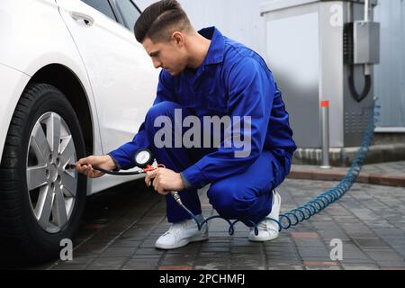 Professioneller Mechaniker, der Reifen beim Autoservice aufpumpt Stockfoto