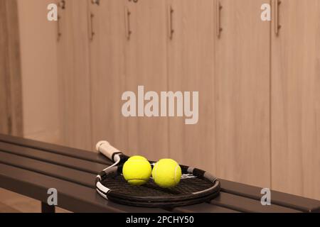 Tennisschläger und Bälle auf Holzbank im Umkleideraum Stockfoto