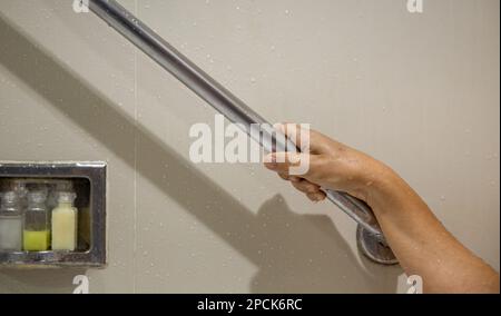 Ältere Frau, die sich zur Sicherheit im Badezimmer am Handlauf festhielt Stockfoto