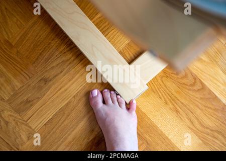 Frau schlug mit dem kleinen Zeh auf die Möbel. Zwischenfall zu Hause. Verletzung des kleinen Fingers des Fußes Stockfoto