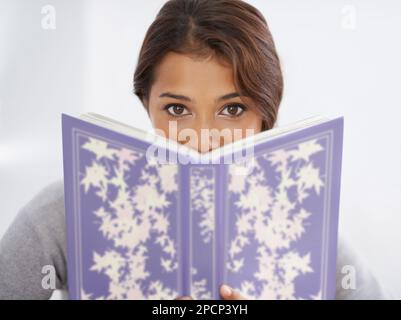 Interessante Lektüre. Porträt einer jungen Frau, die über ein Buch guckt. Stockfoto