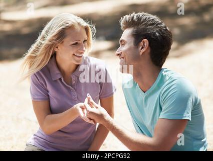 Sag ja... Seitenansicht eines jungen Mannes, der seiner schönen Freundin einen Antrag macht. Stockfoto