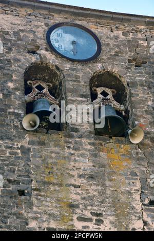 Detail eines alten Glockenturms in einer Kirche, mit zwei Glocken und einer rostigen Uhr Stockfoto