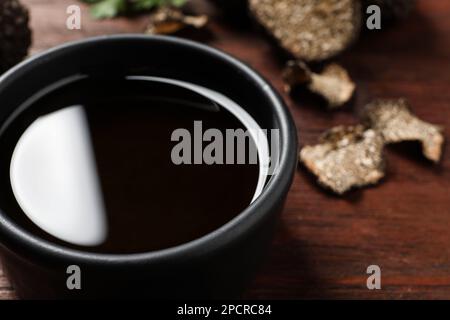 Frisches Trüffelöl in Schüssel auf Holztisch, Nahaufnahme Stockfoto