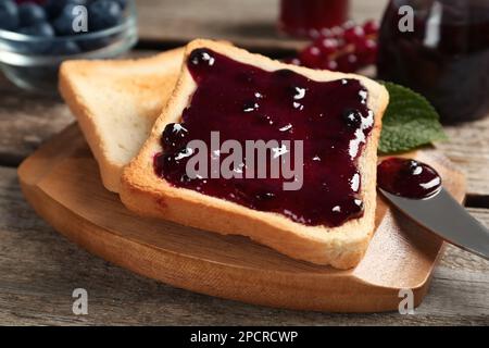 Köstliche Toasts mit Marmelade auf Holzbrett, Nahaufnahme Stockfoto