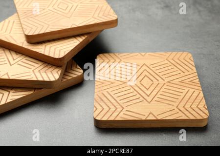 Stilvolle Untersetzer mit Holzbechern auf grauem Tisch Stockfoto