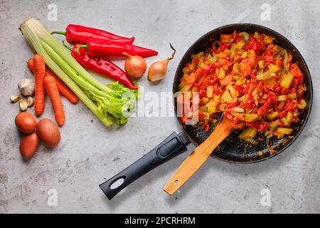 Draufsicht auf rohe Zutaten und verzehrfertige Gemüse-Ragout Stockfoto