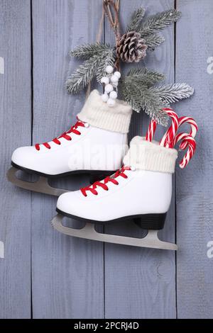 Schlittschuhe mit weihnachtlicher Einrichtung an grauen Holzwänden Stockfoto