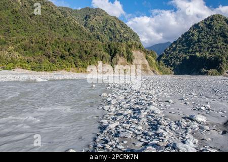 Der Waiho Fluss voller Gletscherschmelzwasser fließt aus der hügeligen Landschaft auf der Südinsel Aotearoa Neuseeland. Stockfoto