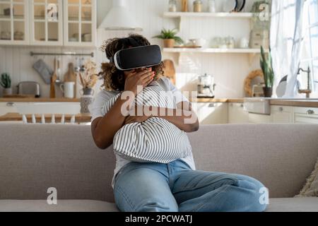 Schockierte afroamerikanische Frau mit Virtual-Reality-Brille hat Angst, wenn sie sich Horror-VR-Videos ansieht Stockfoto