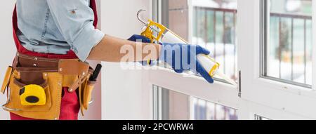 Bauarbeiter versiegelt Fenster mit Versiegelung in Innenräumen Stockfoto