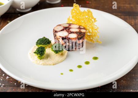 Octopus terrine oder Octopus carpaccio mit Saucen auf einer weißen Porzellanplatte Stockfoto