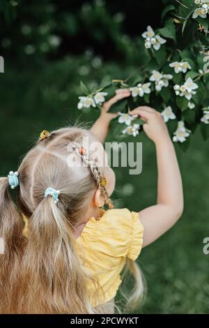 Sommeraktivitäten und Verbindung mit der Natur für Kinder. Süßes kleines Mädchen mit zwei Pferdeschwanzen läuft, tanzt und spielt mit ihrer mutter auf dem grünen Rasen Stockfoto