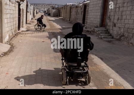 Mashhad Ruhin, Syrien. 14. März 2023. Kriegsbehinderte syrische Flüchtlinge sitzen im Rollstuhl im Lager Mashhad Ruhin. Das Lager Mashhad Ruhin, das früher als "Witwenlager" bekannt war, beherbergt Hunderte syrischer Flüchtlinge im Nordwesten Syriens, von denen die meisten Witwen, alleinstehende Frauen mit Kindern und Menschen mit Behinderungen sind. Kredit: Anas Alkharboutli/dpa/Alamy Live News Stockfoto