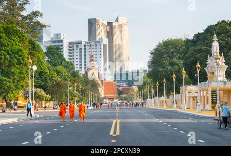 Phnom Penh, Kambodscha-Dezember 23 2023: Gekleidet in traditionellen orangefarbenen Bademänteln, Mönche, viele tragen Gesichtsmasken, machen Sie einen Spaziergang vorbei am Royal Palace Park, auf einem breiten Ro Stockfoto