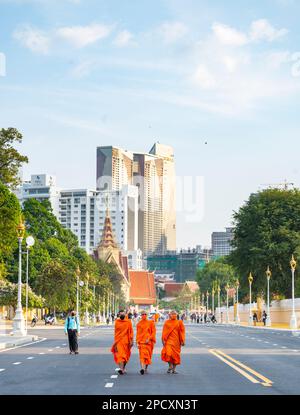 Phnom Penh, Kambodscha-Dezember 23 2023: Gekleidet in traditionellen orangefarbenen Bademänteln, Mönche, viele tragen Gesichtsmasken, machen Sie einen Spaziergang vorbei am Royal Palace Park, auf einem breiten Ro Stockfoto