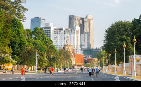 Phnom Penh, Kambodscha-Dezember 23 2023: Gekleidet in traditionellen orangefarbenen Bademänteln, Mönche, viele tragen Gesichtsmasken, machen Sie einen Spaziergang vorbei am Royal Palace Park, auf einem breiten Ro Stockfoto