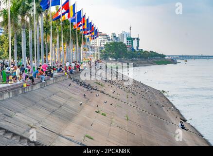 Phnom Penh, Kambodscha-Dezember 23 2023: Der flagengesäumte Riverside Path ist ein beliebter Ort für kambodschanische Familien, um zu entspannen, zu essen, zu beten und Soziali zu kommen Stockfoto