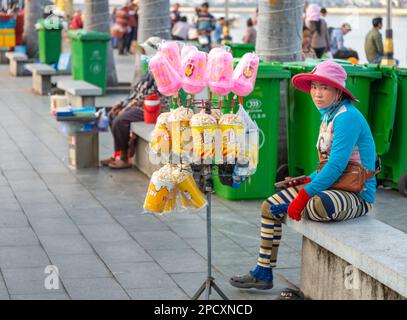 Phnom Penh, Kambodscha-Dezember 23 2023: Die junge Frau, die rosa Zuckerwatte verkauft, wartet geduldig darauf, dass die Khmer-Familien ihre Waren kaufen, während der Stockfoto