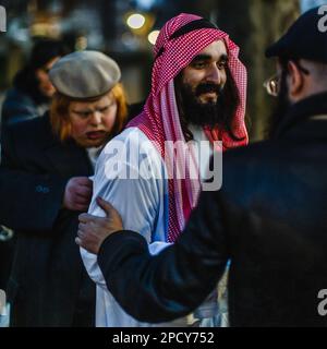 Ein Mann, der als araber gekleidet ist, zusammen mit orthodoxen juden bei Purim, dem jüdischen Karneval in London. Stockfoto