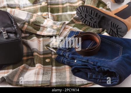 Kleidung. Kariertes Hemd, Jeans, beige Stiefel, Lederrucksack. Schuhe und Kleiderschrank. Moderner Style für Damen. Draufsicht der Kleidung. Damenbekleidung und Accessoires Freizeit Frühling Winter Herbst Outfit. Stockfoto