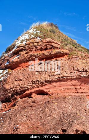 Cullen Bay Golfplatz Moray Schottland blauer Himmel über einem Meer aus altem roten Sandstein umgeben von Schnee Stockfoto