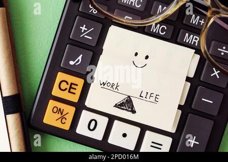 Work-Life-Balance – Konzept für einen abgeschlossenen Arbeitstag: Stift, Brille, Taschenrechner und handgezeichneter Papieraufkleber Stockfoto