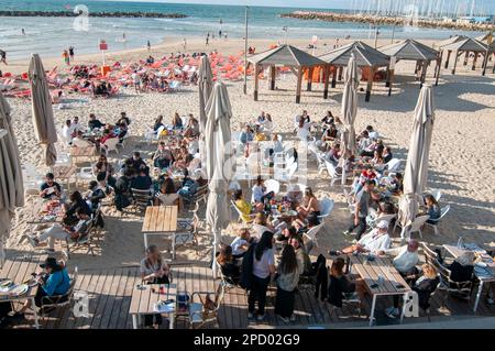 Erhöhte Aussicht auf ein geschäftiges Strandcafé am Nachmittag, fotografiert am Gordon Beach, Tel Aviv, Israel Stockfoto