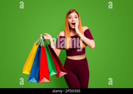 Der Black friday wunderte sich über eine junge Frau mit überraschtem Gesicht, die seine Hand nahe der Wange hält, mit weit offenen Augen und Mund in der anderen Hand, die Einkäufe hält Stockfoto