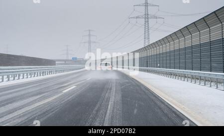 Auto überholt ein anderes Auto auf einer eisigen Straße (deutsche Autobahn). Symbol für gefährliches Fahren auf rutschigen Straßen. Stockfoto