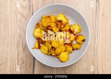 Gekochte Kartoffeln und später in Scheiben auf dem Grill gebacken, auf einem runden Teller liegend. Stockfoto