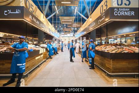 Verschiedene Fischstände, besetzt von Verkäufern in blauen Uniformen. Bei der Fischmarktgenossenschaft in Abu Dhabi, Vereinigte Arabische Emirate. Stockfoto
