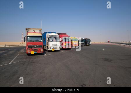 Große Sattelschlepper stehen in Schlange und parken an einer der anderen Haltestellen. Abseits der Autobahn E11 vor Abu Dhabi, Vereinigte Arabische Emirate. Stockfoto