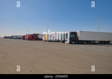 Große Sattelschlepper stehen in Schlange und parken an einer der anderen Haltestellen. Abseits der Autobahn E11 vor Abu Dhabi, Vereinigte Arabische Emirate. Stockfoto