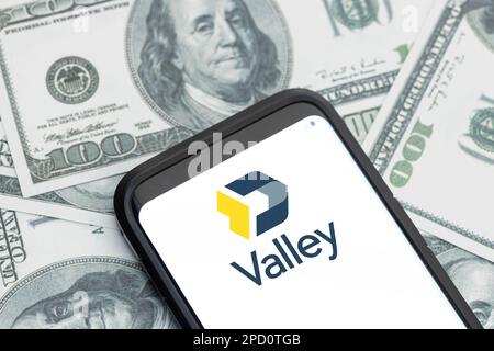 Galicien, Spanien; 12. märz 2023: Logo des Unternehmens Valley Bank Financial Services auf dem Smartphone-Bildschirm und Hintergrund der Dollarscheine Stockfoto