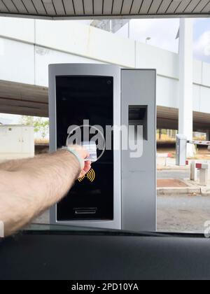 POV männlicher Fahrer Hand in Parkuhr aus dem Auto das Ticket für den Zugang Abfahrt des Parkplatzes Stockfoto