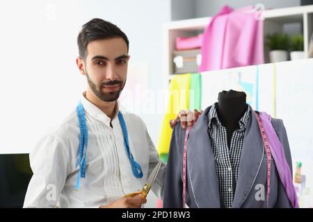 Männlicher Designer mit Schere neben Schaufensterpuppe Stockfoto