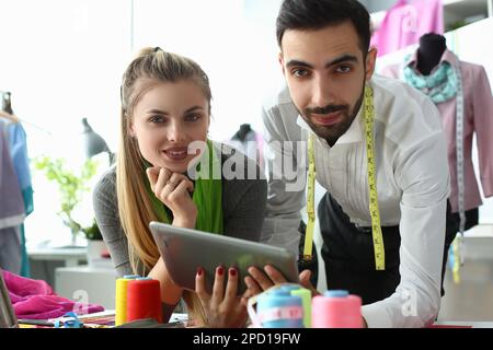 Designer von Männern und Frauen diskutieren in der Werkstatt über neue Kleidungskollektion auf einem digitalen Tablet Stockfoto