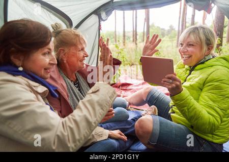 Fröhliche ältere Freundinnen, die High Five geben, während sie im Urlaub im Wald sind Stockfoto