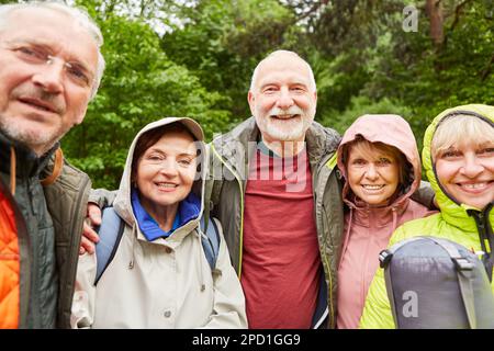 Porträt von lächelnden älteren männlichen und weiblichen Freunden, die während des Urlaubs zusammen im Wald wandern Stockfoto