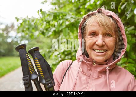 Porträt einer lächelnden Seniorin mit Wanderstöcken und Jacke im Urlaub Stockfoto