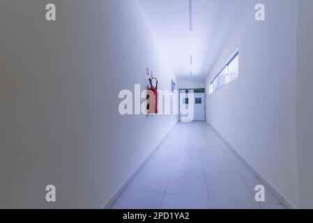 Korridor in einem Krankenhaus in Brasilien mit breiten Wänden, keine Menschen, kaltes Licht, Feuerlöscher und Türen. Stockfoto