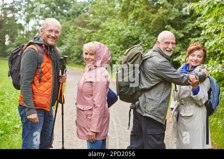 Porträt von glücklichen älteren Männern und Frauen, die auf dem Weg stehen, während sie im Urlaub im Wald wandern Stockfoto