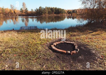 Ein Ziegelkreis, um ein Lagerfeuer am Teich anzünden. Stockfoto