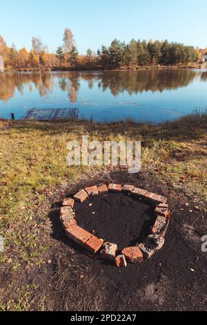 Ein Ziegelkreis, um ein Lagerfeuer am Teich anzünden. Stockfoto