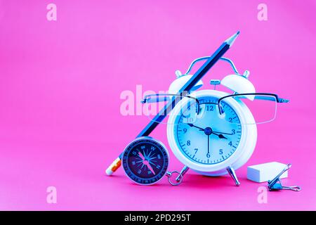 Konzept Bildung oder Geschäft Wecker und Lehrerbrille Geschäftsobjekte isoliert auf farbenfrohem pinkfarbenem Papierhintergrund, Back to School-Konzept Stockfoto